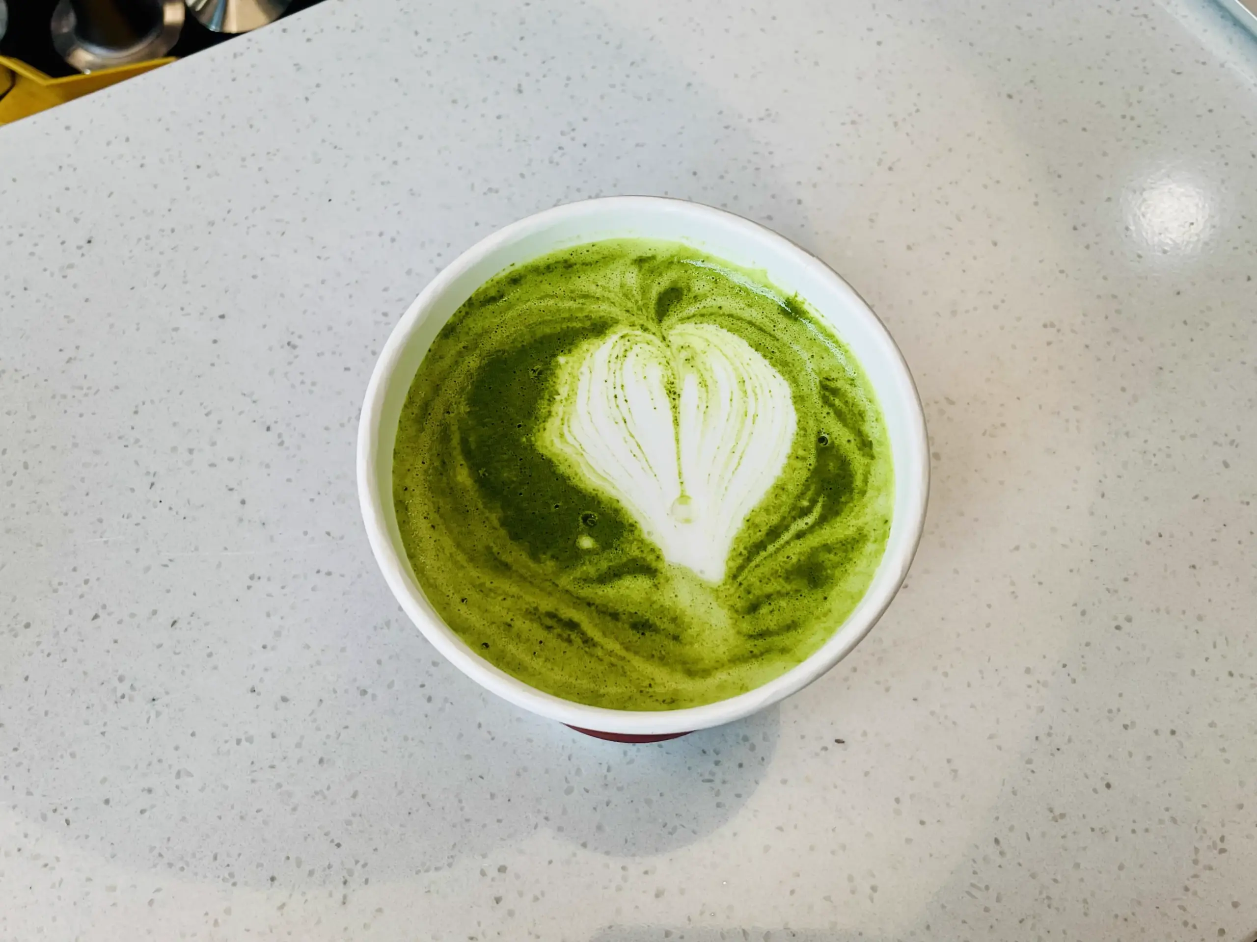 A matcha latte with a heart shape made of milk on the surface.