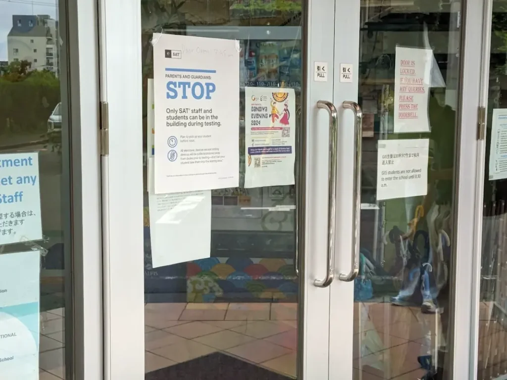 On a glass door, a paper reads, "Parents and guardians, STOP. Only SAT staff and students can be in the building during testing."